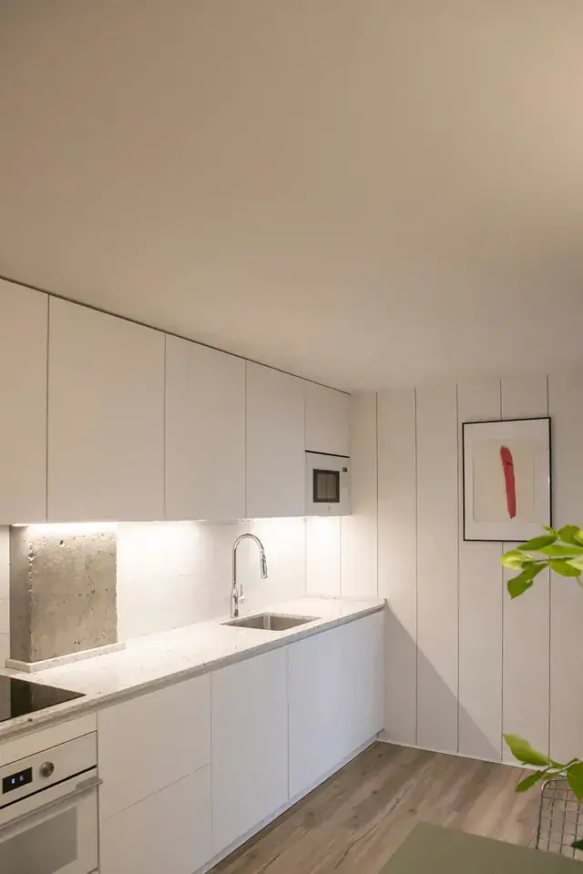 Cocina blanca con encimera continua y luz natural